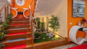 Un escalier moderne avec des tapis rouges disposés en longueur, une décoration murale circulaire et un petit jardin intérieur agrémenté de plantes et de rochers.