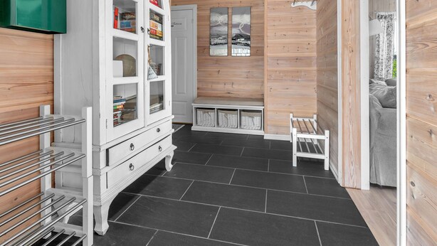 Un intérieur épuré et moderne, avec un meuble blanc, un banc et un sol carrelé.