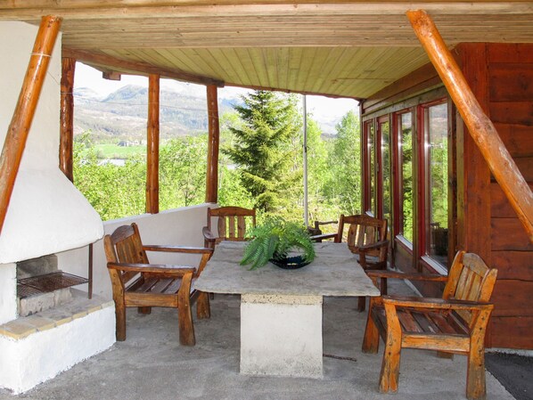 A wooden deck with a stone table and chairs, overlooking a mountainous landscape.