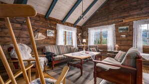 Ein gemütliches Cabin-Interieur mit Holzboden, einer Couch, einem Esstisch und einem Stuhl.