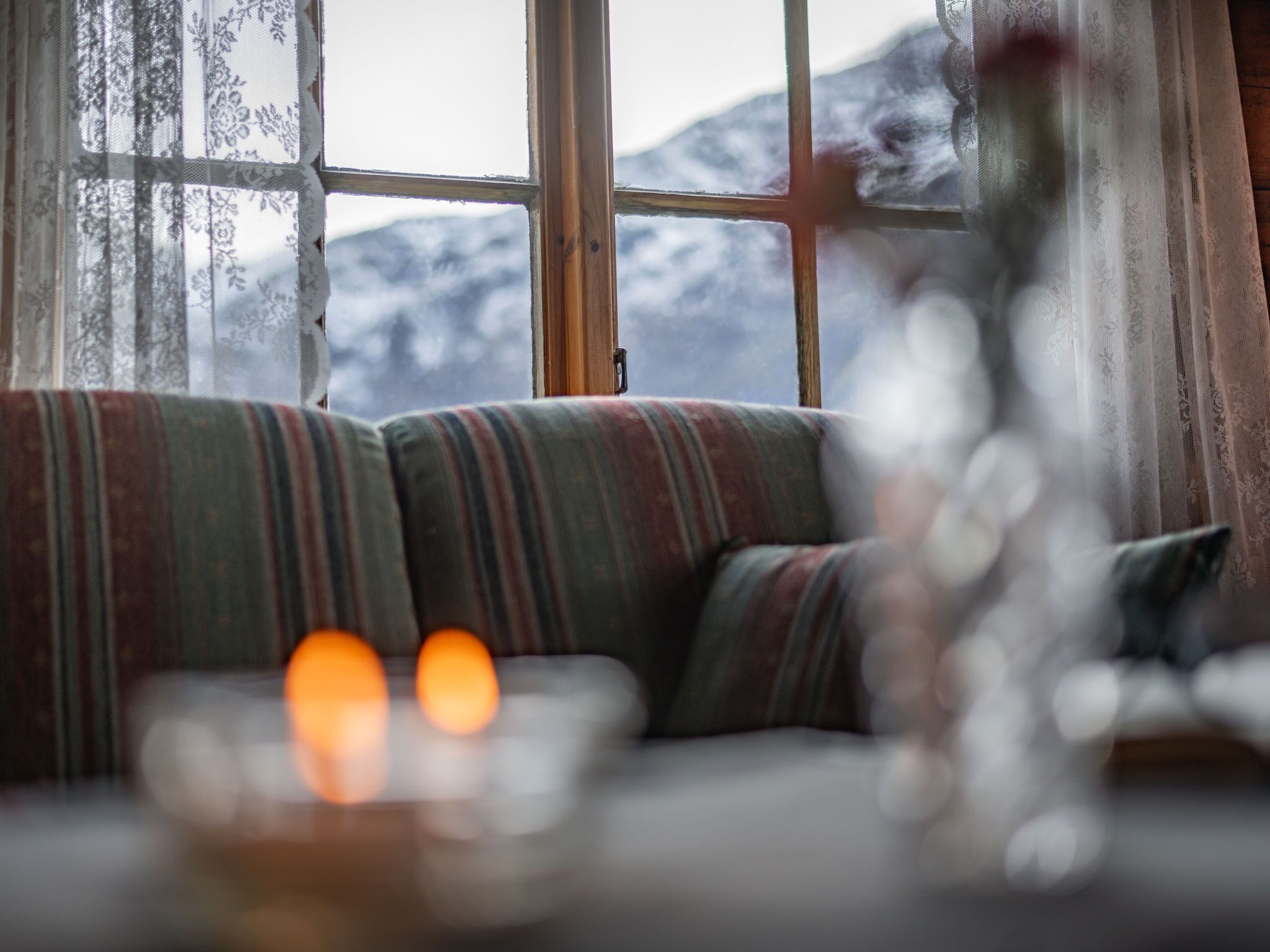 A cozy room with a sofa facing a window overlooking a snowy mountain.