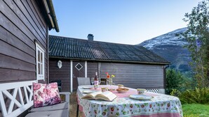 Eine Holzdiele mit Esstisch, einer Bank und Blick auf einen Berg.