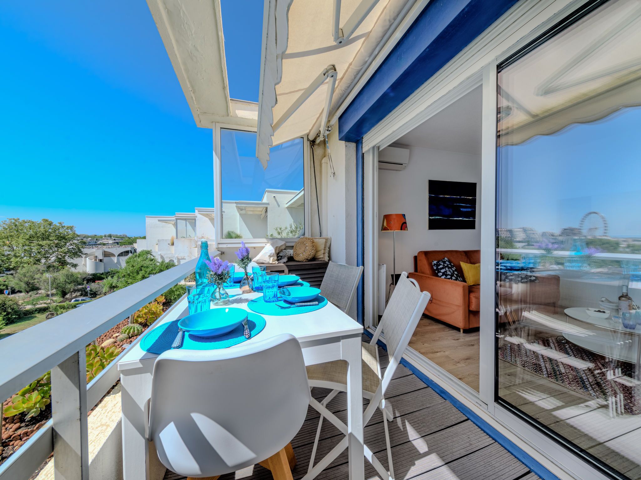 Een balkon met een eettafel gedekt voor vier personen, met uitzicht op de kust.