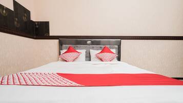 A neatly made bed with a white and red bedspread, two red pillows, and a headboard with a decorative pattern.
