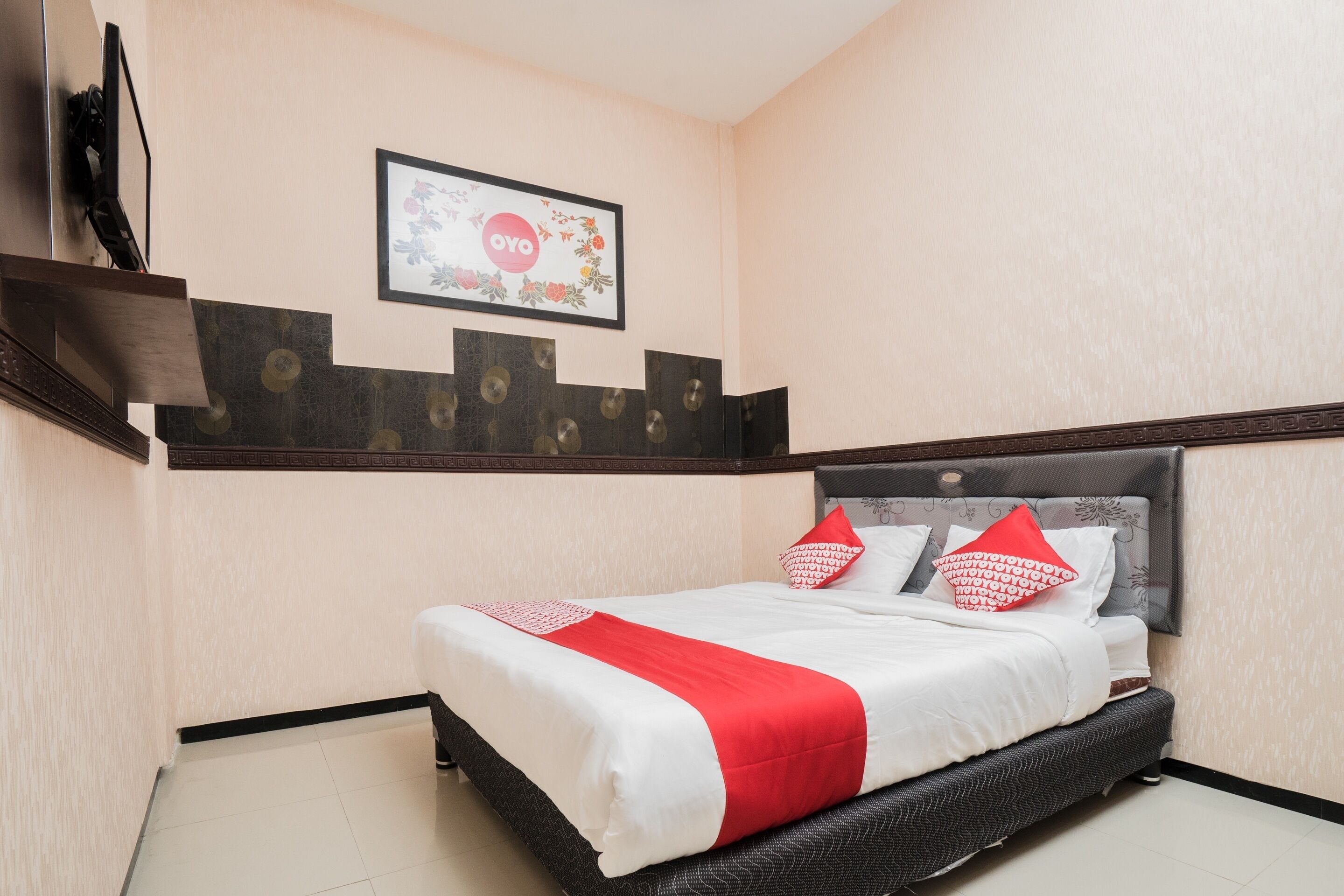 Une chambre d’hôtel avec un lit, une étagère fixée au mur ornée d’objets décoratifs et un tableau encadré au-dessus du lit.
