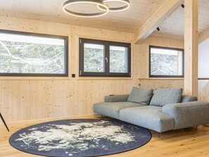 Une pièce aux murs en bois, avec un canapé gris et un tapis rond.