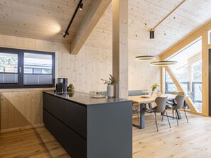 Une cuisine moderne dotée d’un îlot central, de meubles de rangement en bois et d’un coin repas avec une table et des chaises.