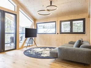 Un salon moderne avec un canapé gris, un téléviseur à écran plat posé sur un pied, et un tapis rond.