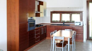 Une cuisine avec des meubles de rangement en bois, une cuisinière et une table à manger avec des chaises.