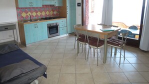 Una cocina compacta con comedor, horno empotrado y ventana con cortinas.