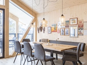 Ein zeitgemäßer Essbereich mit Holztisch, grau gepolsterten Stühlen und Pendelleuchten.