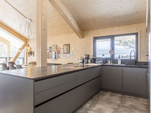 Une cuisine moderne dotée d’un comptoir en granit, d’appareils électroménagers en acier inoxydable et d’une grande fenêtre offrant une vue sur l’extérieur.