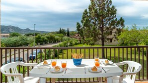 Un balcón con mesa lista para el desayuno, con vistas a un paisaje pintoresco de árboles y montañas.