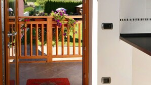 Una habitación con una puerta de madera que da a un balcón con vistas a una ladera boscosa.