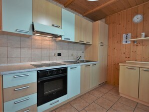 Een koelkast, een oven, kookgerei, borden en bestek