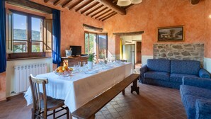 A dining area with a long table set for a meal, wooden furniture, and a stone wall. - La Vittoria by Interhome (Cortona)