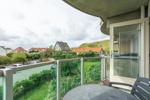A balcony with a table and chairs, overlooking a green landscape and houses. - Apartment in Callantsoog near the dunes (Callantsoog)