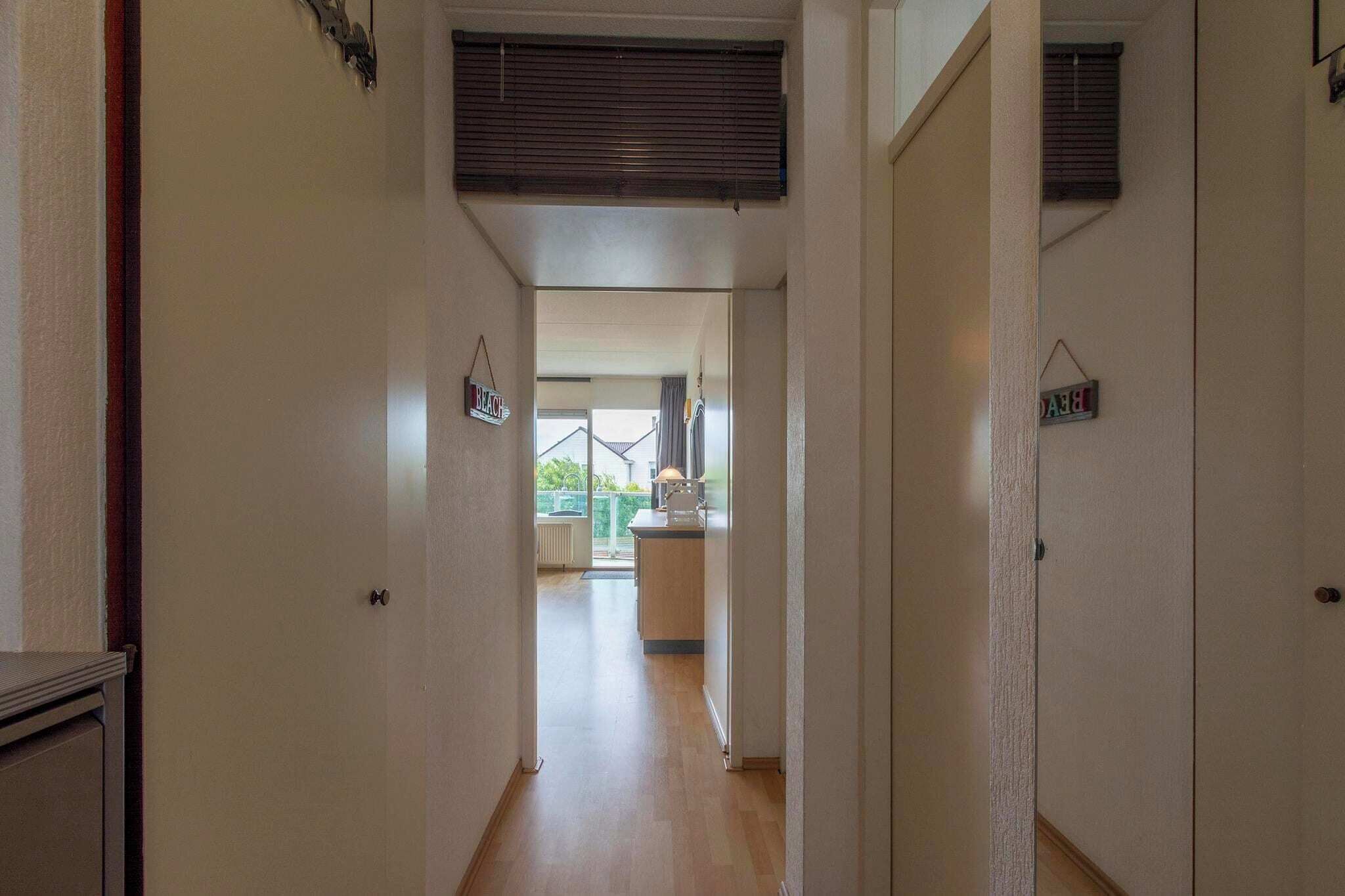A narrow hallway with a kitchen area in the background.