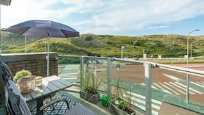 A balcony with a table, chairs, a wicker basket, and potted plants.