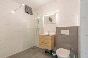 Une salle de bain moderne avec une douche à parois de verre, un meuble-lavabo en bois et des toilettes.