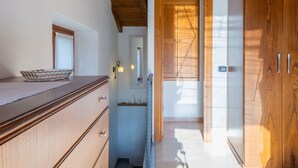 Un couloir étroit avec des armoires en bois, un saladier en verre posé sur un comptoir en bois et un miroir accroché au mur.