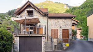 Une maison en pierre avec un balcon, un garage et une vue sur les montagnes.