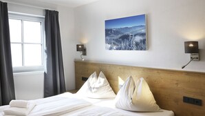 Ein Hotelzimmer mit Bett, einem Fenster mit Vorhängen, einem Wandbild und zwei Wandleuchten.