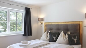 Un lit double avec une tête de lit, deux tables de chevet, une fenêtre avec des rideaux et un luminaire fixé au mur.
