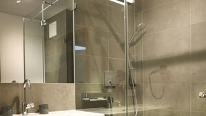Une salle de bain moderne avec une douche à parois de verre, un meuble-lavabo en bois et un grand miroir.