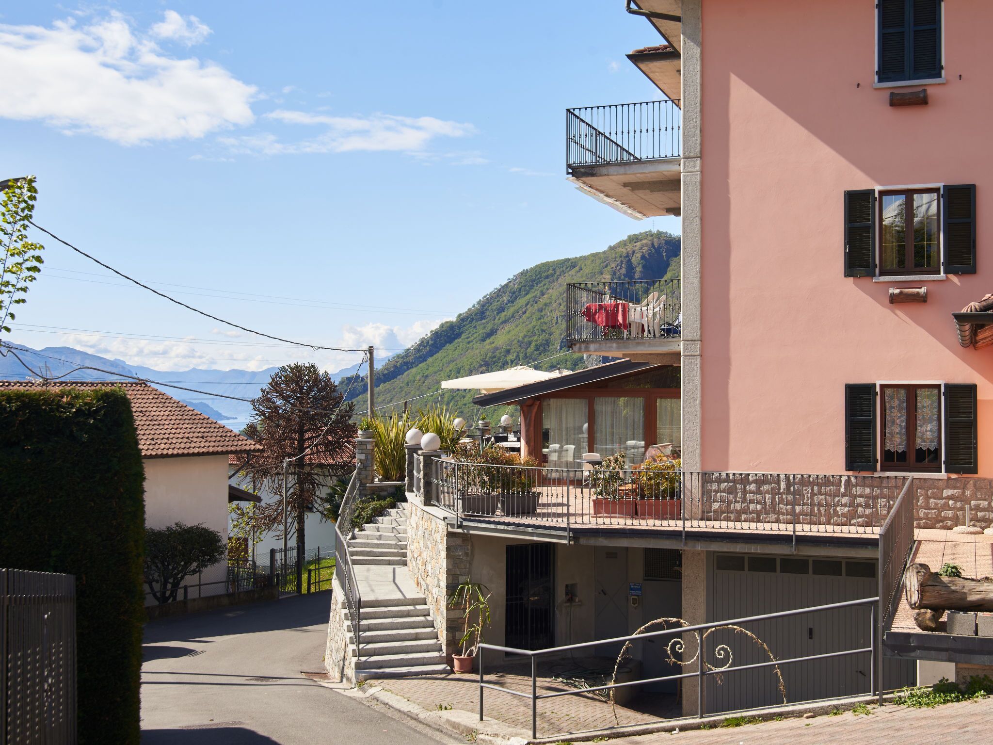A two-story building with a balcony, a staircase, and a view of a mountain.