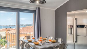 Eine moderne Küche mit großem Fenster, einem für das Frühstück gedeckten Esstisch und einem Edelstahl-Kühlschrank.