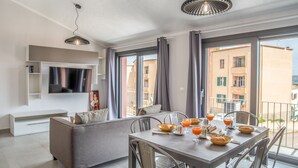 Ein modernes Wohnzimmer mit einer Couch, einem Esstisch, Stühlen und einem an der Wand befestigten Fernseher.