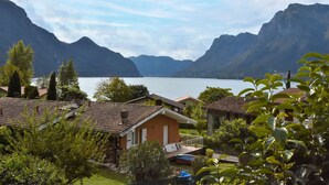 A lakeside property with a view of mountains, a swimming pool, and a well-maintained garden.