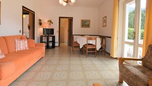A living room with a sofa, a TV, a dining table with chairs, and a chandelier. - Villa Laura by Interhome (Lago d'Idro)
