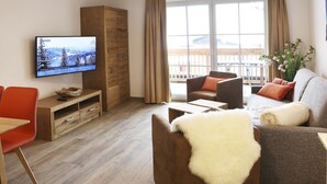 Un salon moderne doté d’un téléviseur à écran plat, de meubles en bois, d’un canapé et offrant une vue sur un balcon.
