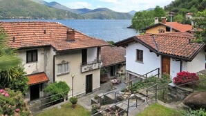 Ein Küstendorf mit terrakottafarbenen Dächern, einer Steintreppe und Blick auf das Meer und die Berge.