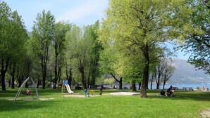 Ein Park mit einem Spielplatz, Picknicktischen und einem See im Hintergrund.