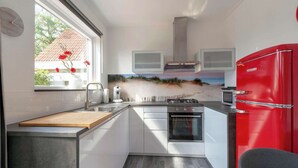 Une cuisine de taille réduite avec un réfrigérateur rouge, une cuisinière et un évier.