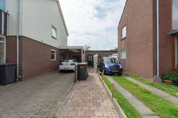 A narrow alleyway between two brick buildings with parked cars on either side.