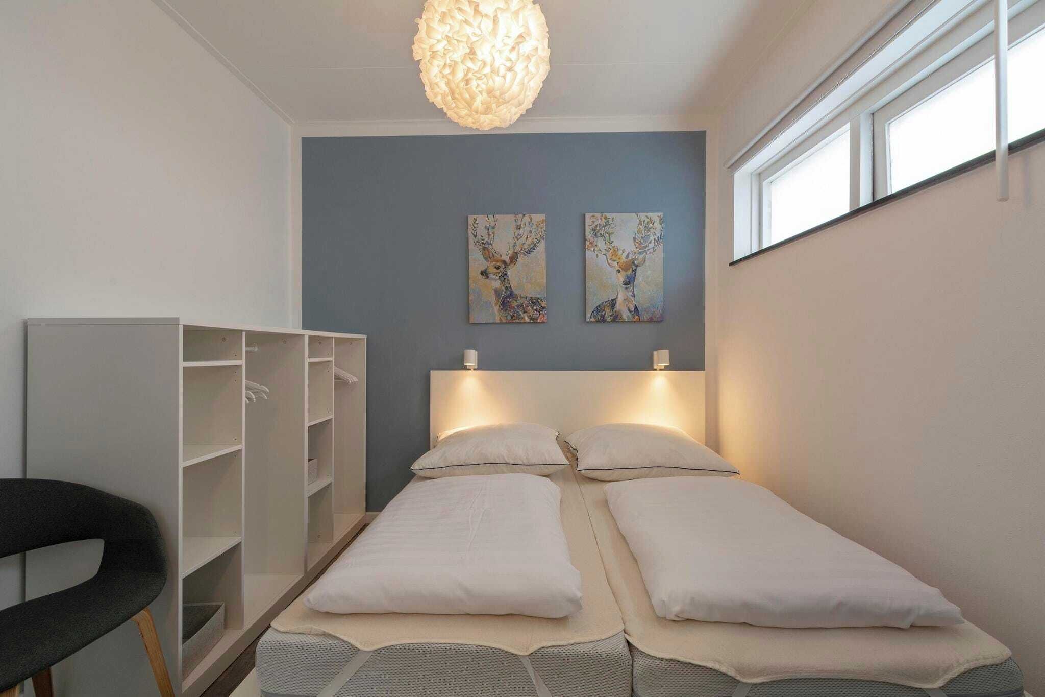 Ein Zimmer mit einem Bett, zwei Wandbildern, einem Kleiderschrank und einem Sessel.