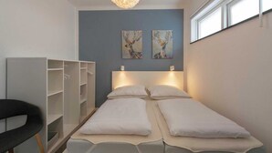 Une pièce comprenant un lit, deux tableaux accrochés au mur, une armoire et une chaise.