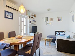 A modern living room with a dining area, a sofa, and a television. - Vacation home Ana by Interhome (Brač/Supetar)
