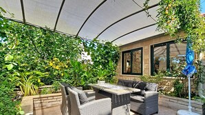 An outdoor patio with wicker furniture, a table, and a blue umbrella. - Vacation home Ana by Interhome (Brač/Supetar)