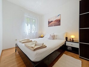 A neatly made bed with folded towels, a bedside lamp, and a wall-mounted picture.