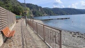 Ein Steinweg führt zu einem Ufer mit einer hölzernen Bank und einem Metallgeländer.
