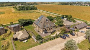 Une propriété rurale comprenant plusieurs bâtiments, un espace de stationnement et des champs environnants.