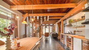 Une cuisine moderne avec des poutres en bois, un coin repas doté d’une table en bois et un escalier menant à un autre niveau.