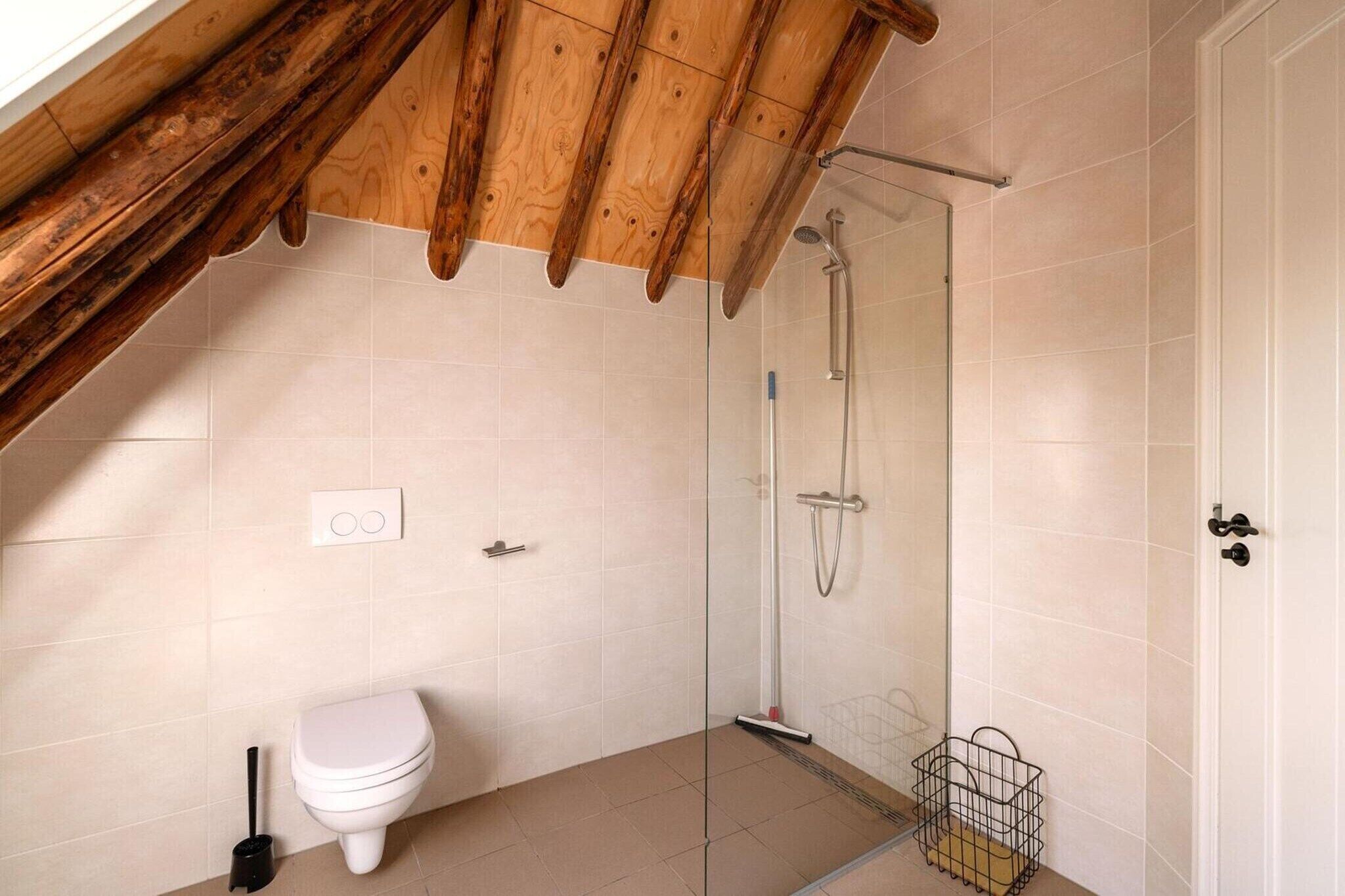 Ein kleines Badezimmer für eine Person mit Dusche, Toilette und einem sichtbaren Stromanschluss.