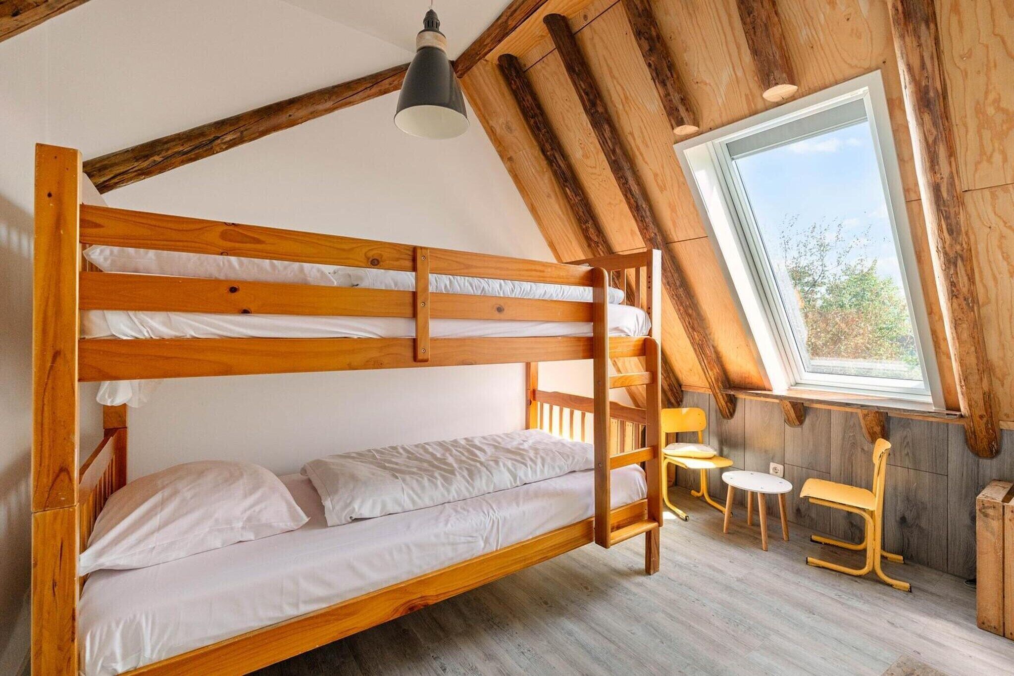 A bunk bed room with a sloped ceiling, a window, and a table with chairs.