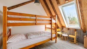 A bunk bed room with a sloped ceiling, a window, and a table with chairs.